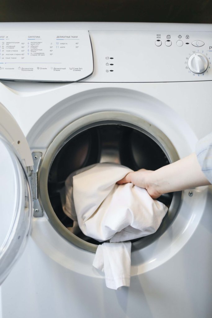 Clothes being put in the washing machine to be cleaned by the laundry detergent
